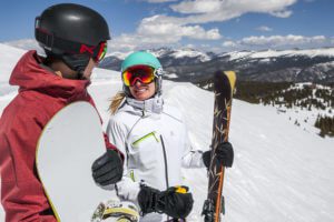 Skier and snowboarder couple smile at each other