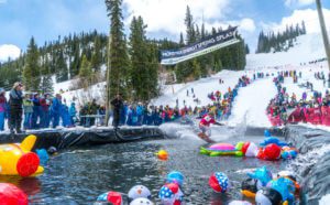 Snowboarder splashes into the Winter Park Resort pond skim competition