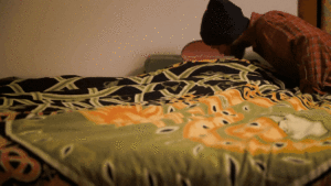 Snowboarder tucks his snowboard into bed and kisses it goodnight