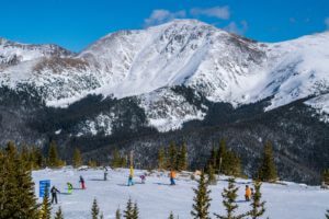 Perry's Peak on a blue bird day, with skiiers riding down the Parsenn Bowl Territory